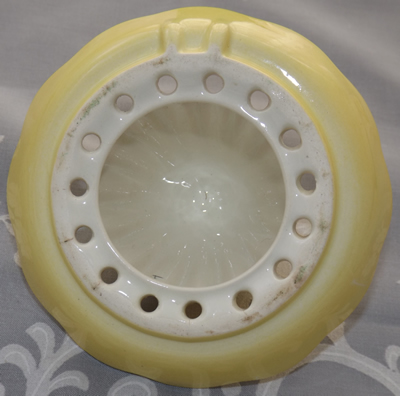 The bottom of a cream yellow Carlton Ware juicer top showing the two positioning notches