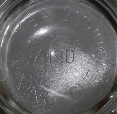 The embossed "MEASURING AND MIXING CUP" on the base of a 2 piece clear glass juicer