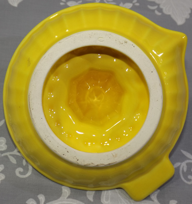 Bottom view of a yellow ceramic saucer short pip collector juicer