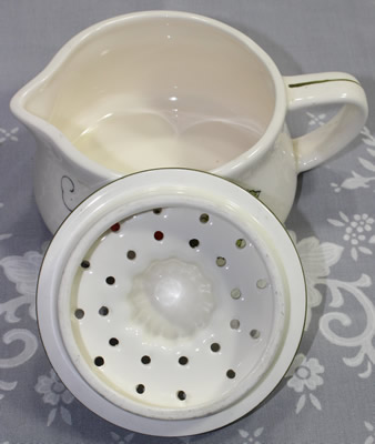 The 2 parts of a white ceramic with strawberries juicer 