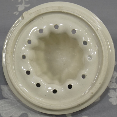 Bottom view of a white with blue and brown trim ceramic reamer