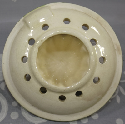 Bottom view of a cream with green and brown trim ceramic reamer