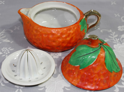 The 3 parts of an orange green and gold pear shape ceramic juicer