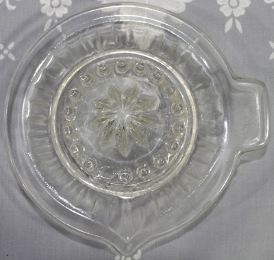 Top view of a clear glass flat rim fluted/panelled saucer juicer