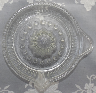 Top view of a tear drop pattern clear glass saucer juicer