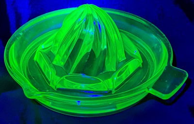 An Anchor Hocking Glass Company green glass tab handle spiral juicer under UV light