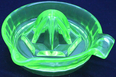 A Hazel Atlas unembossed green glass juicer under UV light