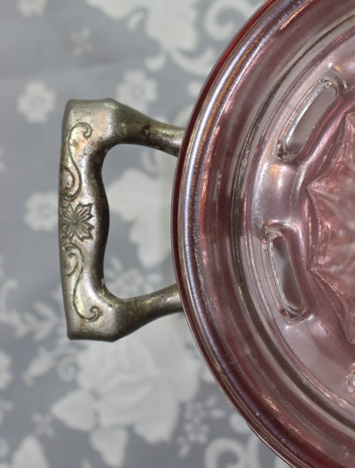 The engraved handle of the frame for a pink Jeannette ice bucket juicer