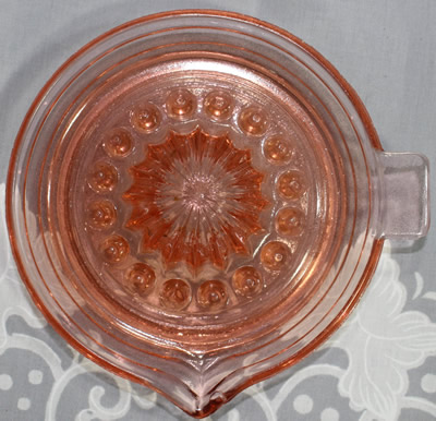 Top view of a salmon pink Jeannette Glass Co. juicer with pip collectors 