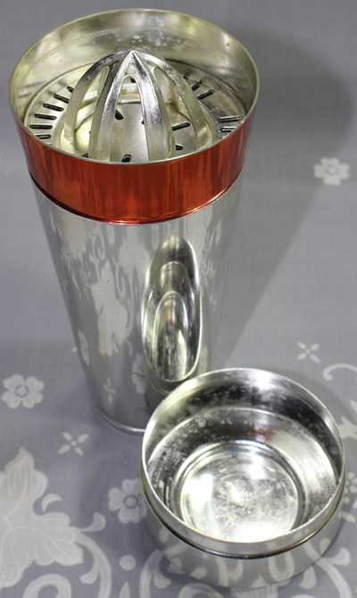 An open orange and silver anodised aluminium cocktail shaker with a juicer