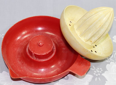 The 2 parts of a Duperite red and cream plastic juicer