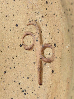 The potter's mark on a wheat pattern on a hand thrown clay pottery juicer