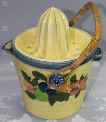 Yellow with multicoloured fruit ceramic biscuit barrel with cane handle juicer