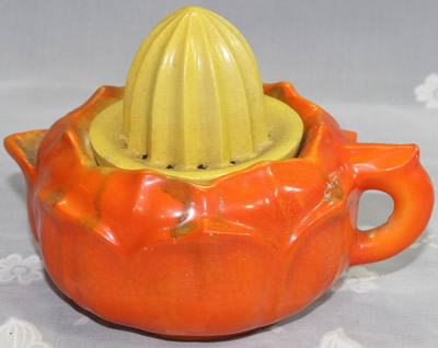 An orange jug with a small yellow top ceramic juicer