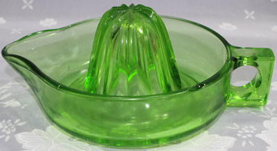 A large unembossed green glass loop handle juicer